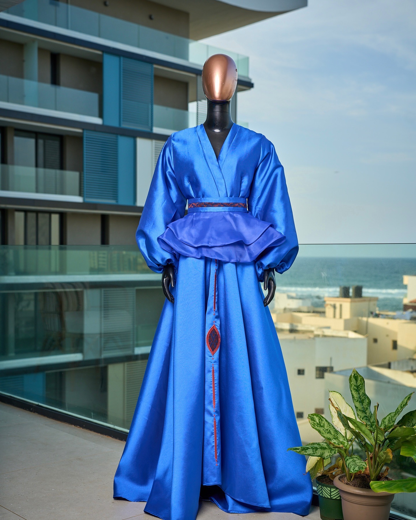 Ensemble bleu roi — peplum satin et jupe brodée face à l'océan