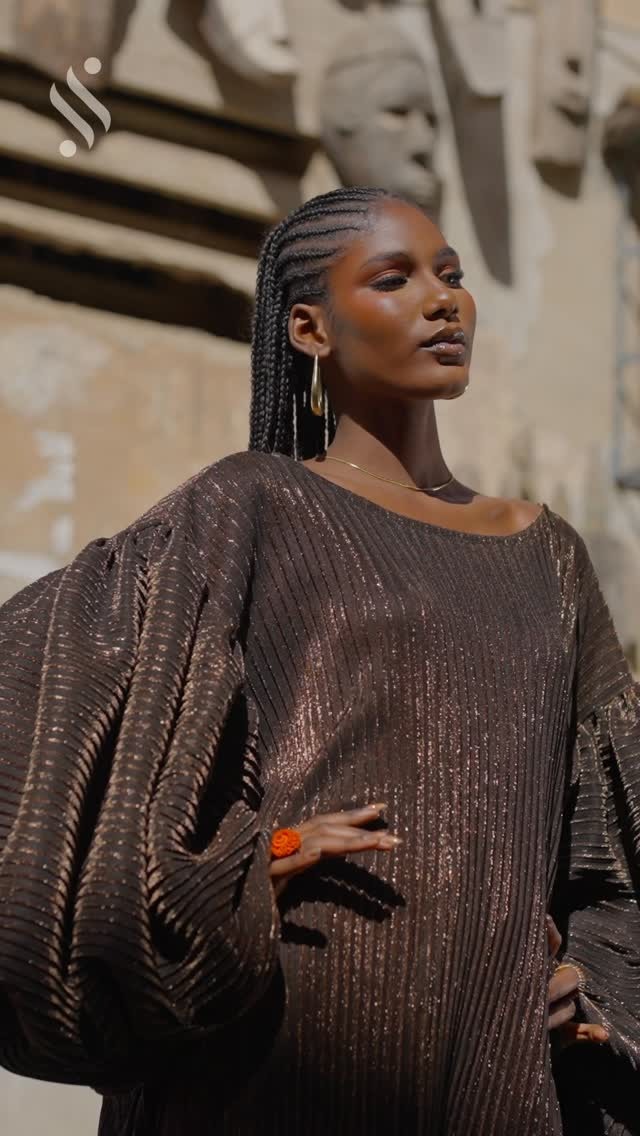Robe plissée bronze — campagne Paris devant façade sculptée