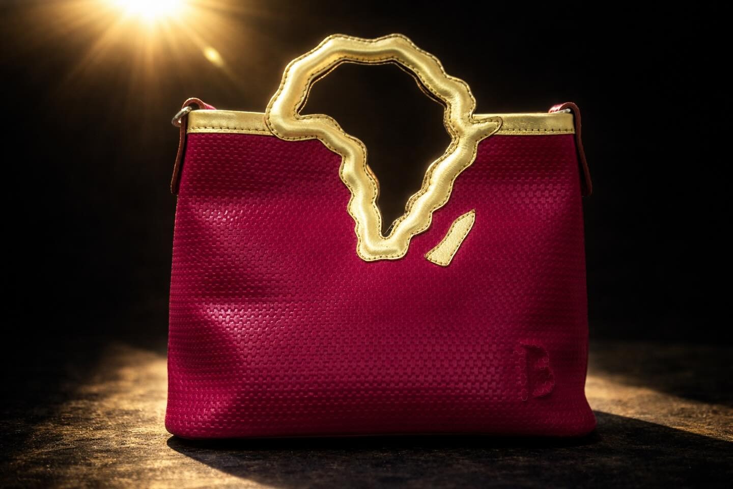 Le cabas Afrique en cuir tressé fuchsia, poignée dorée.