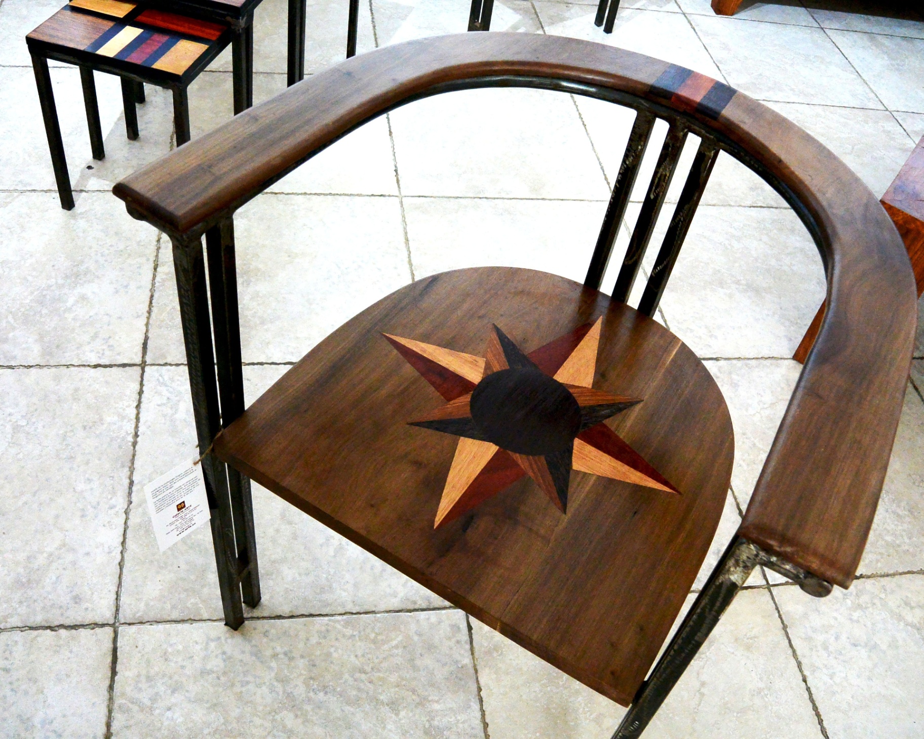 Fauteuil Étoile : structure métal forgé, dossier bois cintré, assise en marqueterie rayonnante.