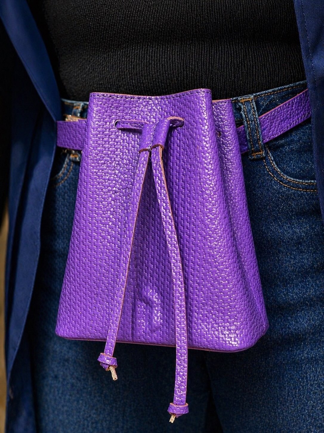 Mini bucket bag violet en cuir tressé, porté ceinture.