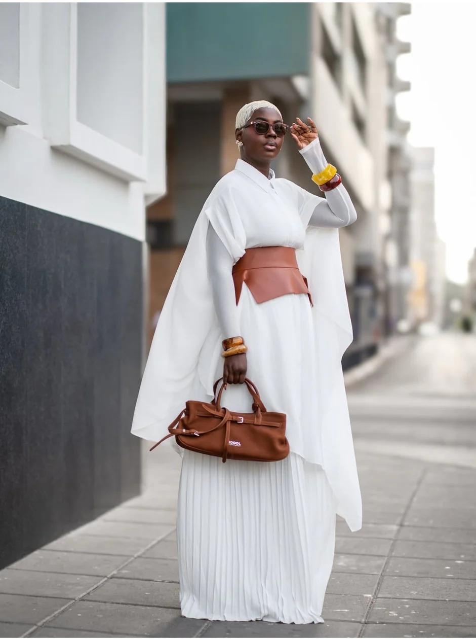 Silhouette urbaine — cape blanche plissée, ceinture cuir cognac et sac IDOOL.