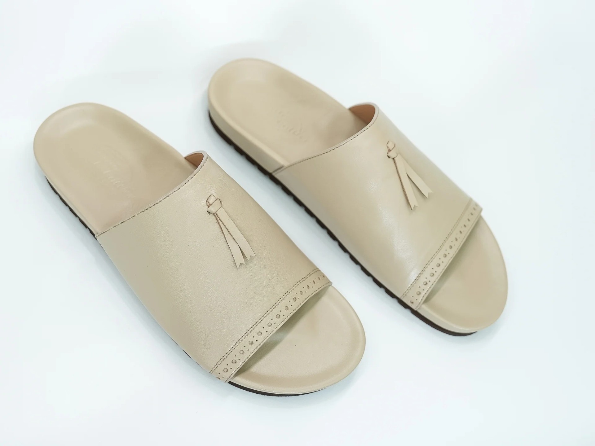 Claquettes cuir beige à pompons — signature relaxée