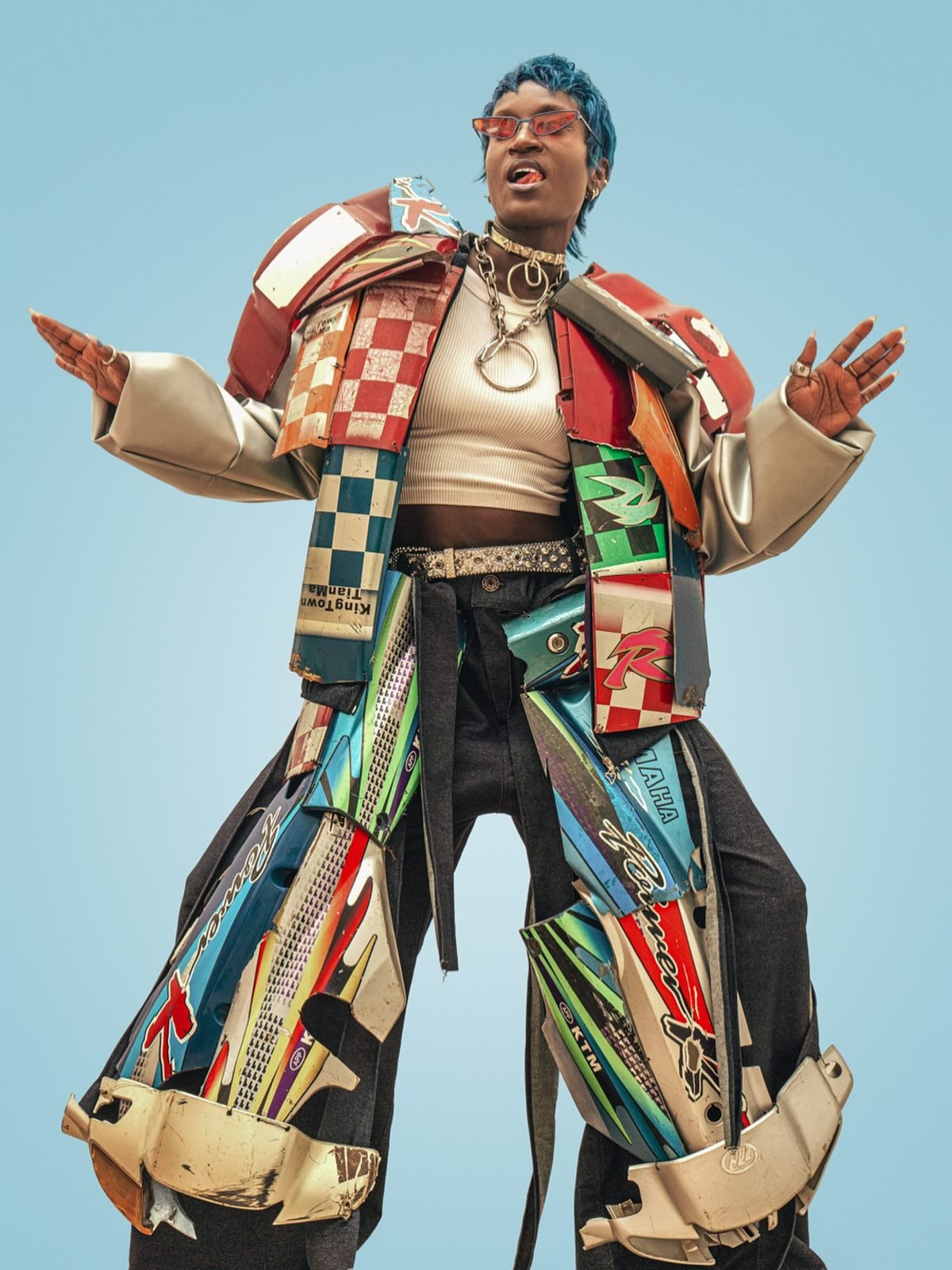 Armure de carénages de moto recyclés — sculpture wearable sur ciel bleu.