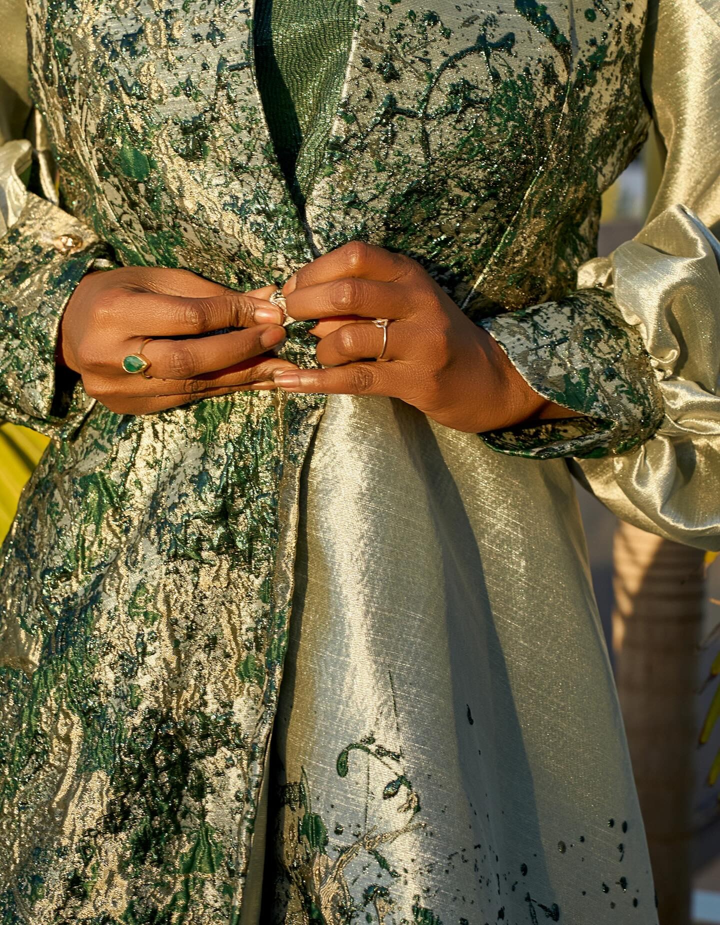 Boubou brocart vert et or — détail des mains et bagues