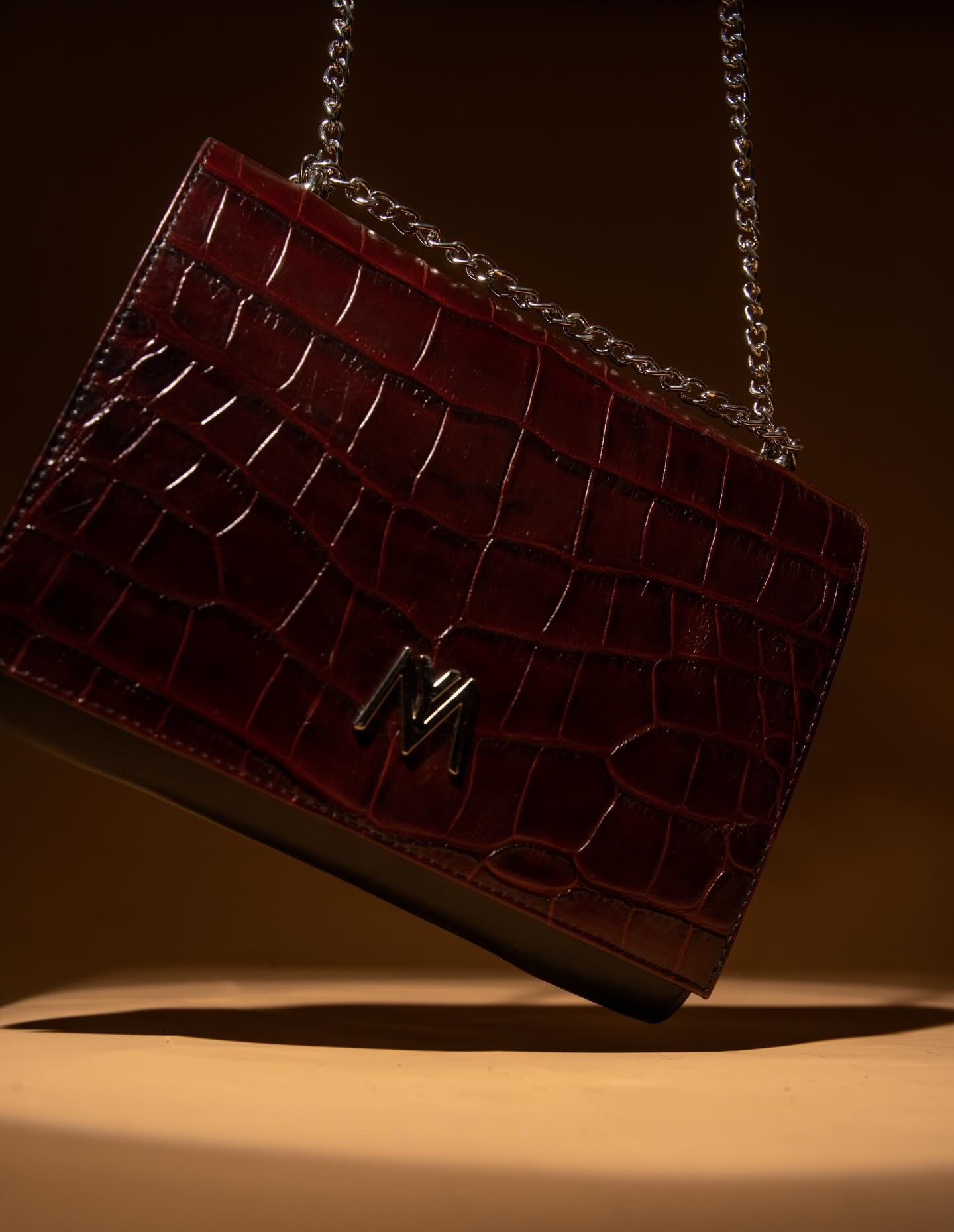 Clutch croco bordeaux — mise en scène lumière chaude
